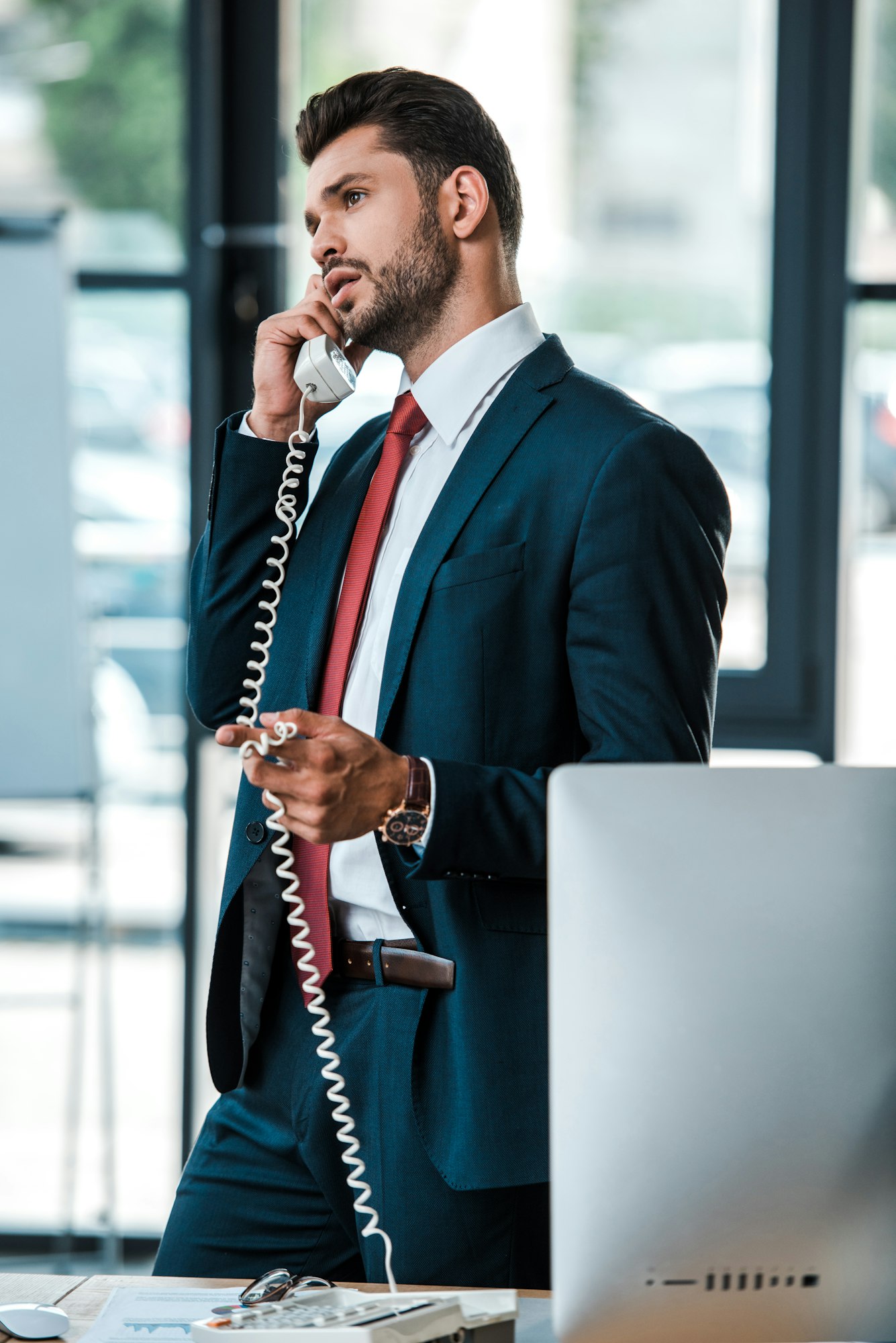 selective focus of handsome bearded businessman talking on retro phone in office
